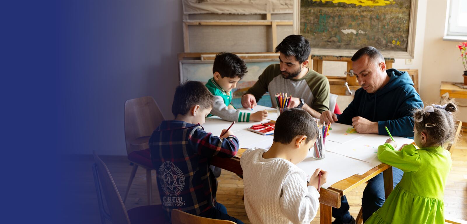 Children drawing together at a table with caregivers